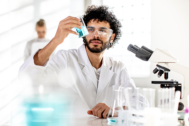 Laborant beim kontrollieren einer Flüssigkeit im Reagenzglas Laborant beim kontrollieren einer Flüssigkeit im Reagenzglas