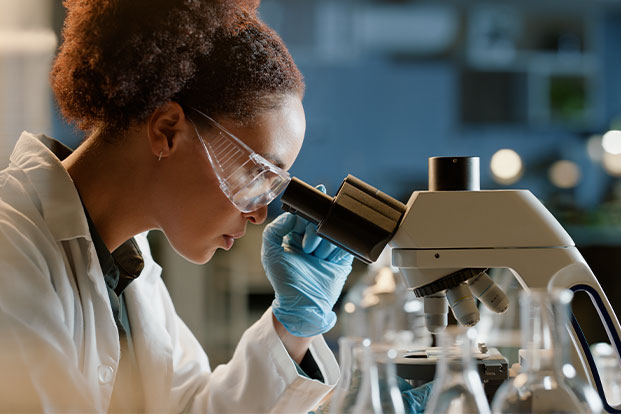 Forschung und Analyse im modernen Labor Wissenschaftlerin im Labor schaut durchs Mikroskop, umgeben von Reagenzgläsern