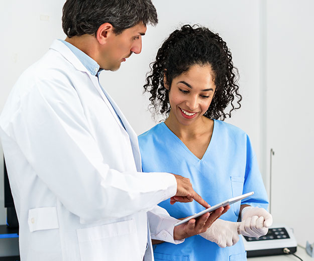 Eine medizinische Fachkraft bespricht gemeinsam mit einem Arzt Informationen auf einem Tablet und unterst&uuml;tzt die Patientenversorgung.