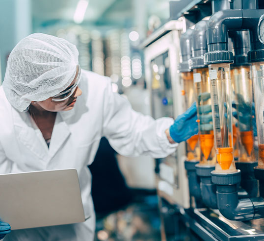 Eine Fachkraft &uuml;berpr&uuml;ft eine technische Anlage und dokumentiert Messwerte in einer Laborumgebung.