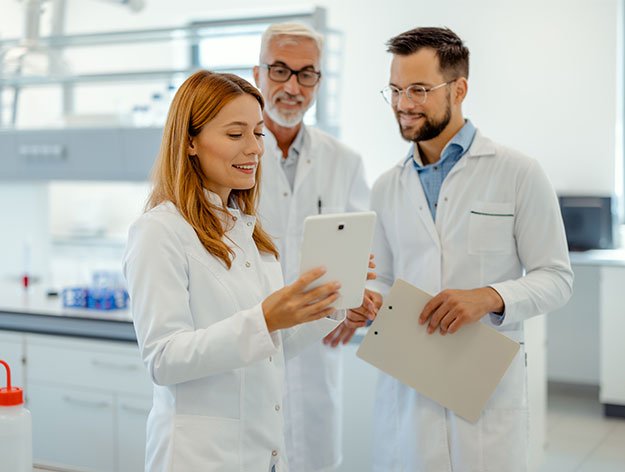 Mehrere Laborfachkr&auml;fte besprechen Ergebnisse und tauschen Informationen mithilfe eines Tablets aus.