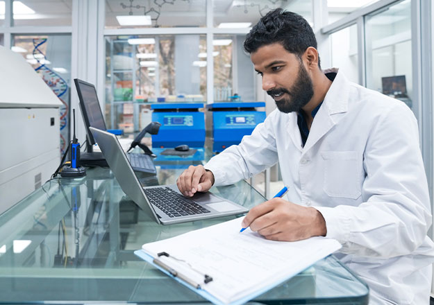 Ein Laborleiter dokumentiert Ergebnisse am Laptop und koordiniert Arbeitsabl&auml;ufe in einer Forschungseinrichtung.