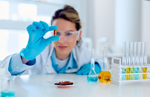 Eine QC-Analystin untersucht eine Laborprobe und kontrolliert die Qualit&auml;t eines Produkts anhand analytischer Verfahren.