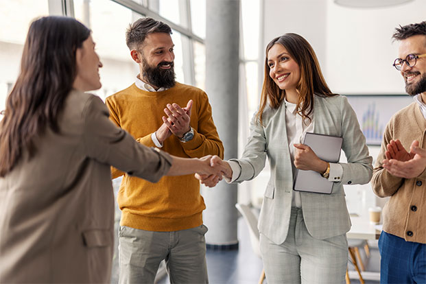 Eine Managerin begr&uuml;&szlig;t eine neue Kollegin per Handschlag und f&ouml;rdert eine offene, wertsch&auml;tzende Zusammenarbeit im Team.