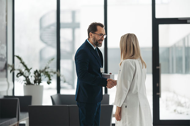 Ein Personalmanager begr&uuml;&szlig;t eine Bewerberin und f&uuml;hrt ein pers&ouml;nliches Gespr&auml;ch im Rahmen des Recruiting- und Einstellungsprozesses.