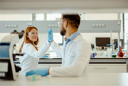 Teamarbeit und Erfolg im Forschungslabor Zwei Wissenschaftler im Labor feiern ein erfolgreiches Experiment mit High-Five