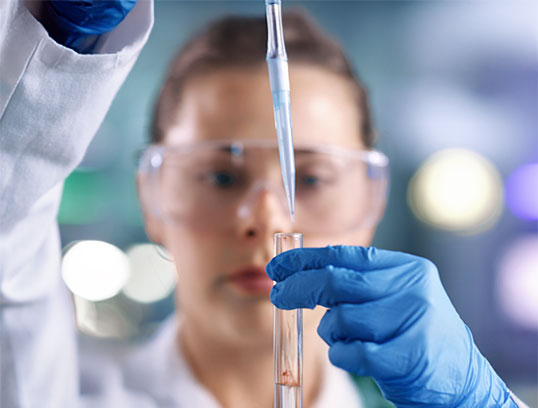 Präzise Laborarbeit in der Forschung Wissenschaftlerin pipettiert Flüssigkeit ins Reagenzglas mit Schutzkleidung